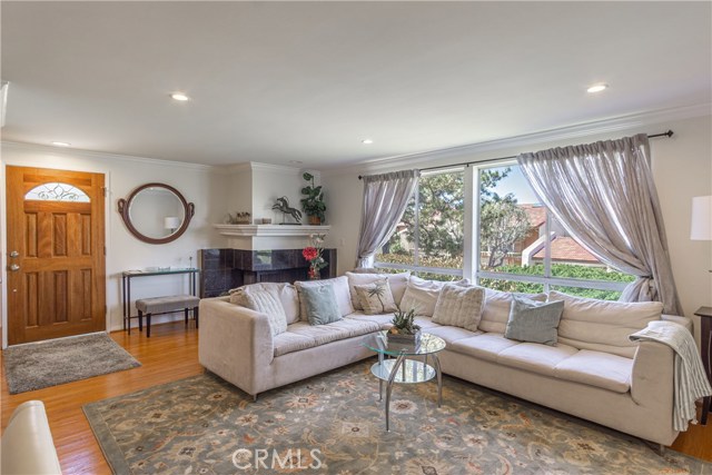 Open living room with gas fireplace, wood floors, crown molding, recessed lighting