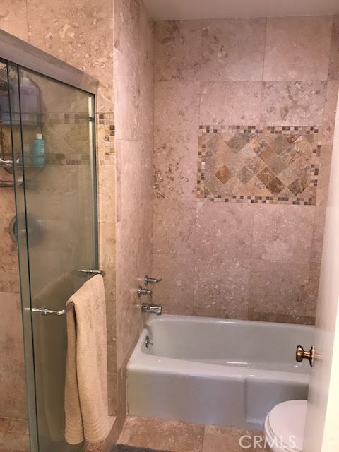 Master bedroom ensuite bathtub with inlaid tile and enclosed shower