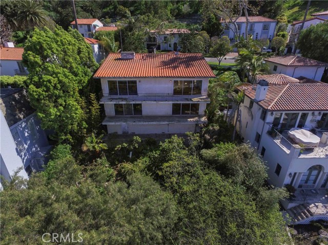 View of the back of home from above.  2 stories with balconies and a lower level underneath the home with a workshop area.