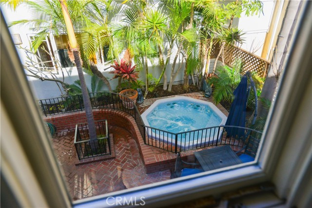 A view of the patio and spa from the upstairs master bedroom. Notice the windows behind the palm trees. those windows lead to the separate office that has limestone floors, bamboo cabinets and desktops and elegant 3/4 bath.