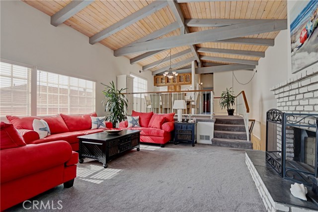 Large open living room, with fireplace, balcony and beamed ceilings. View of the dining room and kitchen from living room.