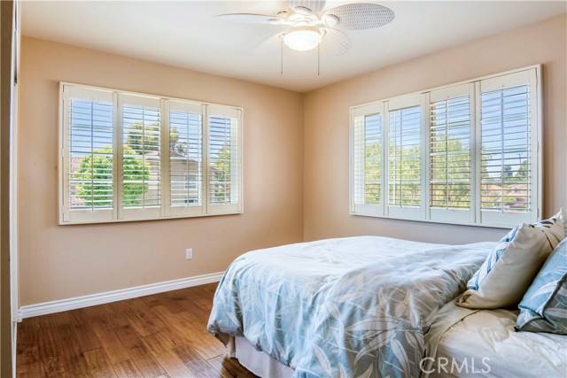 Bedroom #2 with hardwood floors. ceiling fan, and shutters