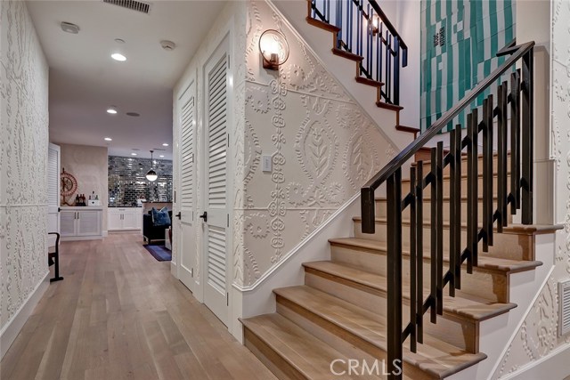 Stairway to lower level Family Room, ensuite bedroom, powder room and Theater.  Wallpaper resembles floral medallions with a 3-D effect.