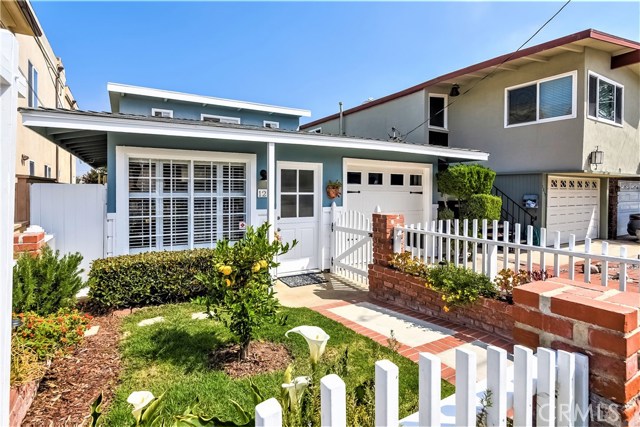 The landscaped front yard has grass, flowers, hedges and a lemon tree