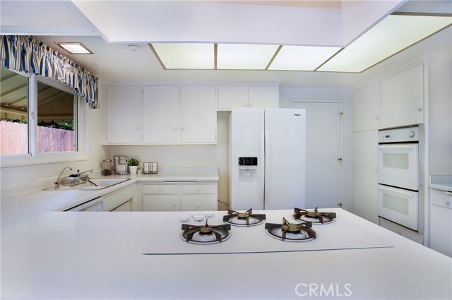 An abundance of white cabinets gas cooktop and newer fridge (included)