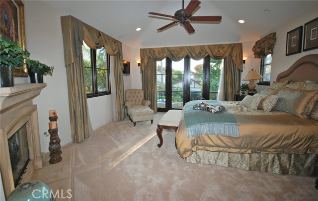 Master bedroom with ceiling fan, fireplace, balcony