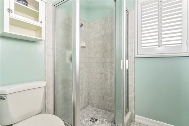 The master bath has a shower and a window with a plantation shutter