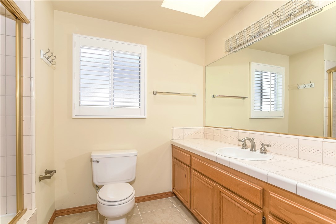 The master bath is well sized with a tub, large vanity, bright lighting, a skylight and a full wall mirror.