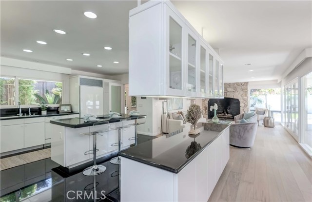 Spacious kitchen with glossy cabinets, recessed lighting, black tile flooring.