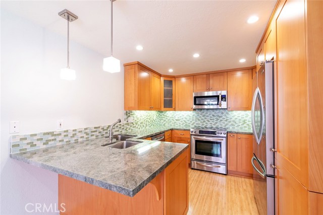 Remodeled Kitchen with breakfast bar, granite counter tops, glass tile backsplash, new stainless steel appliances and bamboo flooring