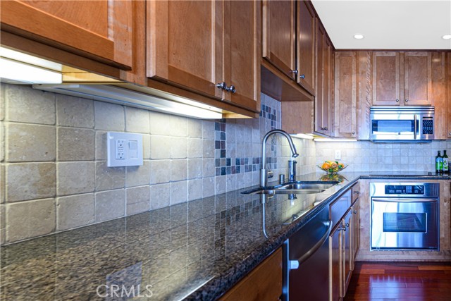 View of Kitchen with built-in appliances, granite counter and stone backsplash