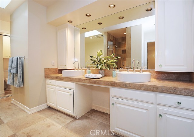 Master bath with His/Her sinks, stone floors, separate tub, walk-in shower, and toilet alcove, plus two wardrobes.