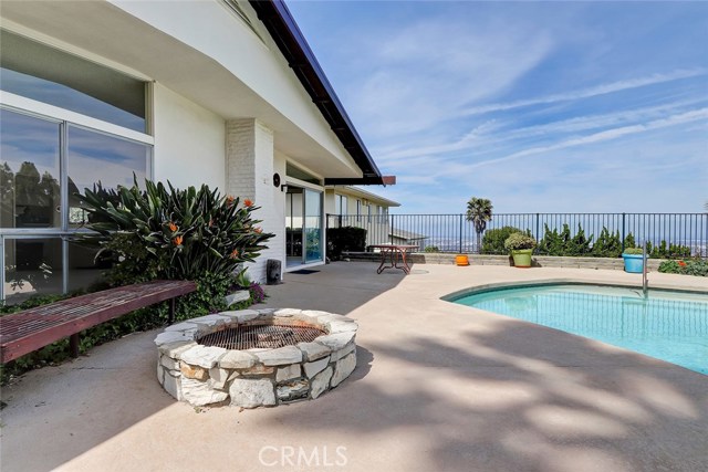 LOOKING EAST ACROSS THE FIRE PIT, POOL, AND REAR OF THE HOME.