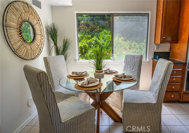 Cheery breakfast nook area off kitchen + den.  There is a doorway to the left that goes back to garage & laundry and a hallway that circles back to living room. There is a powder room off that back hallway as well.