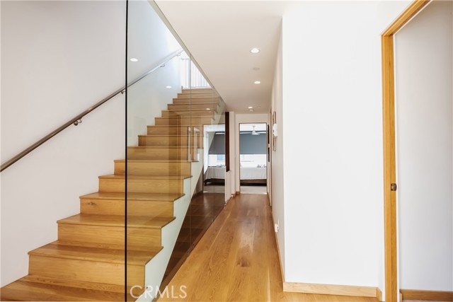 Sleek, glass-walled staircase leads to the main living level, three bedrooms on entry level.