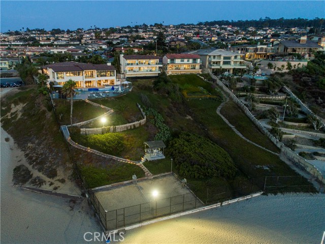 An evening shot of the two properties.  Notice the private sand volleyball court ON the beach!