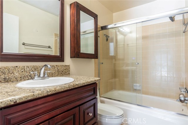 Bathroom mimics the upgrades of the kitchen with granite counters, new cabinets, and travertine floors