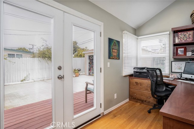 Office or den opens to deck, detached garage and backyard. The office has built-in desk, shelving and drawers. There are additional shelves to the left of the French doors.