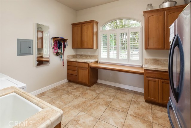 Laundry room with built-in ironing center, sewing table, sink, lots of cabinets, tile floors.