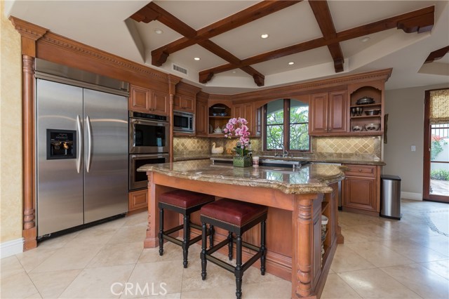 Gourmet kitchen with bar seating cooking island, custom cabinetry, stainless appliances, double ovens