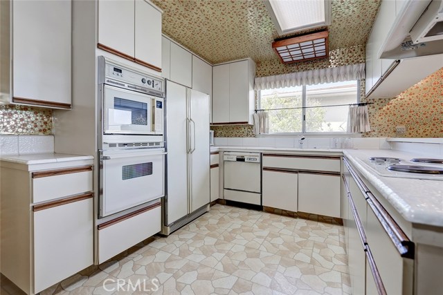 NICE LIGHT AND BRIGHT KITCHEN WITH REFRIGERATOR, OVEN, MICROWAVE, DISHWASHER, AND STOVE TOP COOKING WITH LOADS OF CABINETRY.