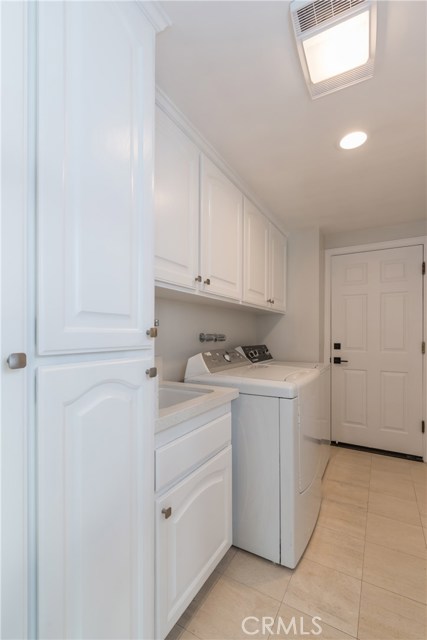 Huge laundry room has tons of storage cabinets, sink, and door opening directly into the 3 car garage.
