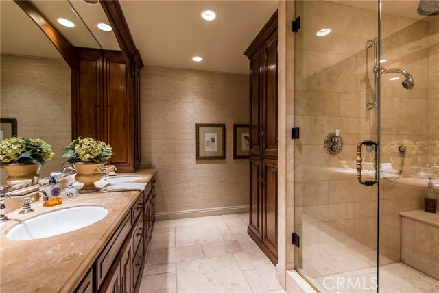The private master bath is a luxurious, spa-like retreat with natural stone counters, Travertine flooring, over sized steam and rain head shower with seamless shower door. An exquisite remodel with the finest fixtures and hardware. Custom, wood built-ins add a stately touch while providing precious storage.