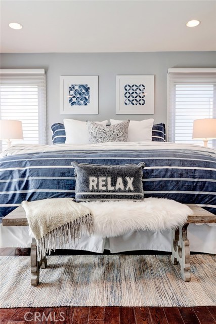 Light and bright master bedroom with recessed lighting, hardwood floors and custom window treatments.
