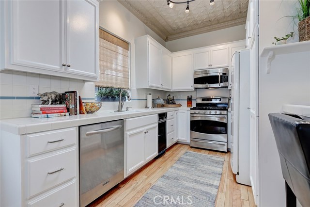 freshly painted cabinets with new hardware, stainless steel appliances and tin ceiling complete this cozy kitchen.