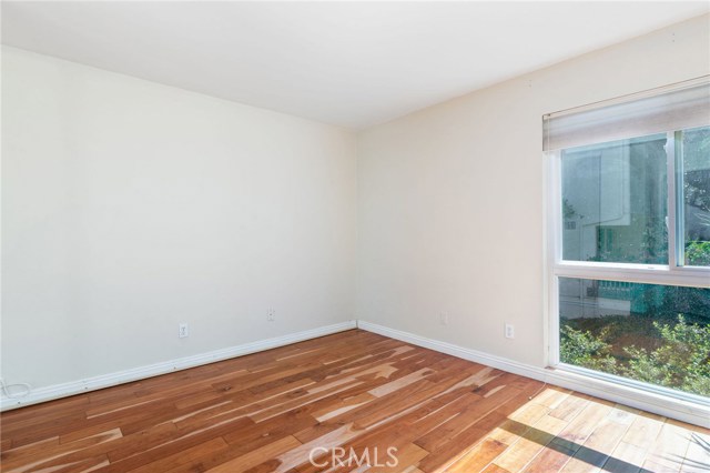 Bedroom also features hardwood floors and a large window letting in natural light and courtyard views