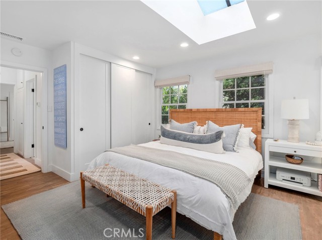 Light & bright primary bedroom featuring skylight, custom window coverings, and closet built ins