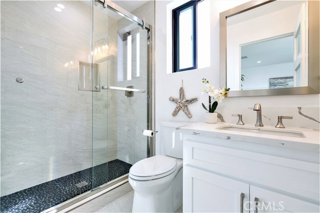 The 2nd Master Bathroom has a Shower with Porcelain Walls, Pebble Stone Floor, Moen or Kohler Fixtures, Seamless Glass Enclosure, Vanity with Thick Slab Carrara Caesarstone Counter Surface and Self-Closing Drawers and Cabinet Doors