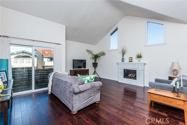 Living room with soaring ceiling, hardwood floors, large windows, balcony, and a modern fireplace.