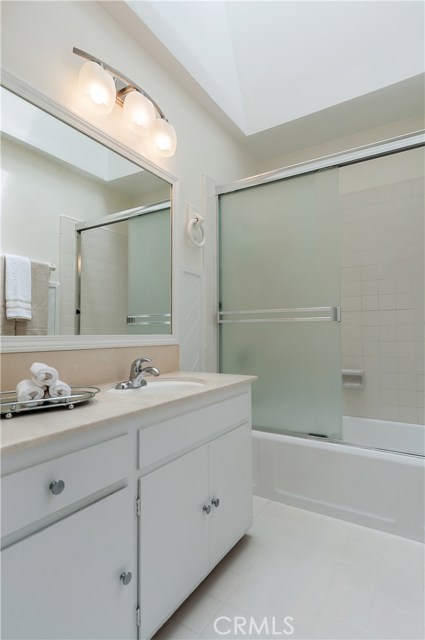 Full bath in hallway with gigantic skylight, tiled floors & tub/shower combo.