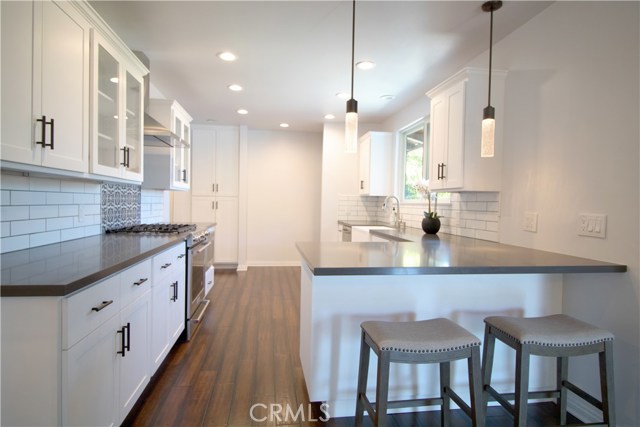 Kitchen boasts white cabinetry w/self-closing drawers & doors, gray quartz counter-tops, Kitchen Aid appliances/including microwave drawer, gorgeous large farm sink, recessed lighting, decorative tiles w/Spanish flair over stove and an Island area which opens to the dining room.