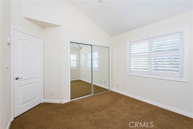 Rear west-facing bedroom with vaulted ceilings and plantation shutters.