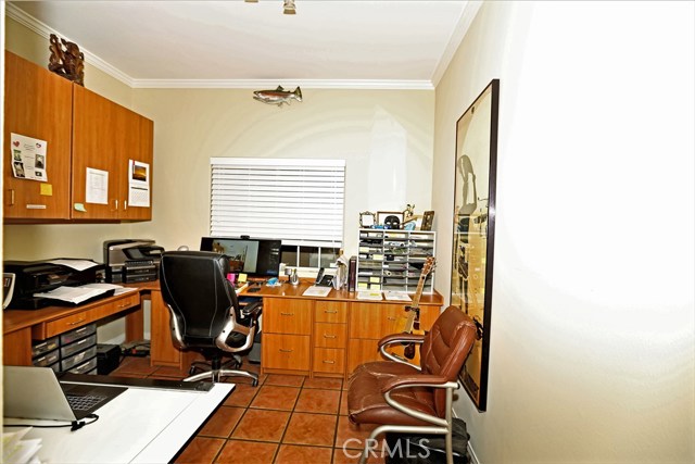 Office off kitchen with built-in casework and tile floor.