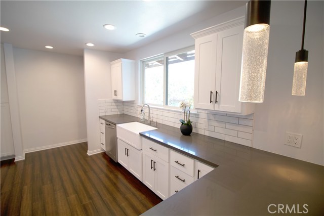 Kitchen boasts white cabinetry w/self-closing drawers & doors, gray quartz counter-tops, Kitchen Aid appliances/including microwave drawer, gorgeous large farm sink, recessed lighting, decorative tiles w/Spanish flair over stove and an Island area which opens to the dining room.