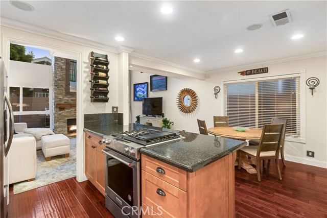 The gorgeous kitchen is upgraded with custom cabinetry, dark granite countertops and peninsula, newer stainless steel range cooktop, and stainless steel refrigerator and dishwasher.