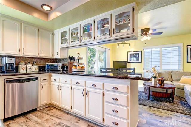 Sunny, light-filled kitchen with breakfast bar, beautiful tile backsplash, tons of cabinet storage, stainless appliances, granite counters, recessed lighting, adjacent family room, and backyard access.