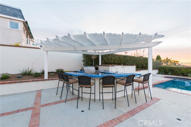 Lovely outdoor kitchen with sink, BBQ, and fridge + tons of bar seating!  Let the parties begin!