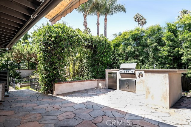 Outdoor kitchen with grill, sink, refrigerator and storage drawers.  To the left are garden ready raised planters - grow your own vegetables!  To the right is a fire-pit then a grassy area