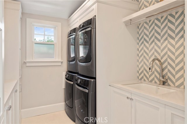 Laundry room with dual washers and dryers, utility sink, folding counter and plenty of cabinet space