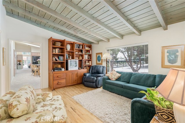 Spacious living room with bay window and wood floors. Rough hewn ceiling. So much charachter!