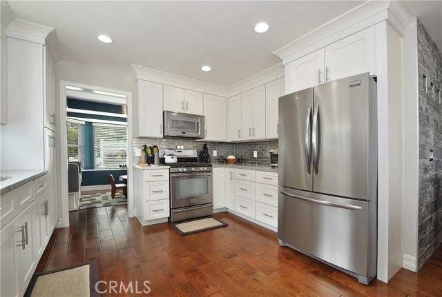 Matching stainless steel appliances compliment hardwood flooring and backsplash.