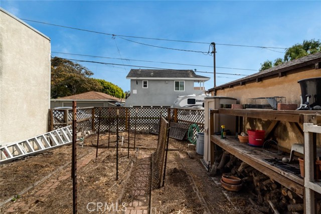 Raised bed vegetable gardens with high quality composted soil. Alley is behind this area. 2 car garage with newer sectional door is at right. Garage was not remodeled. New garage could be built with living area on top and that would have really nice PV and ocean views.