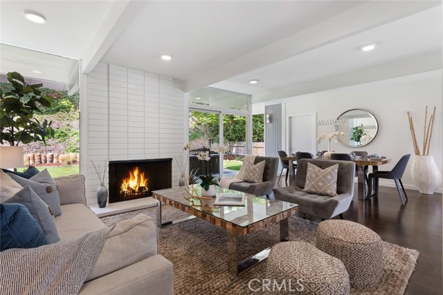 Wonderful open plan living room with wood floors, fireplace and walls of glass overlooking the large backyard