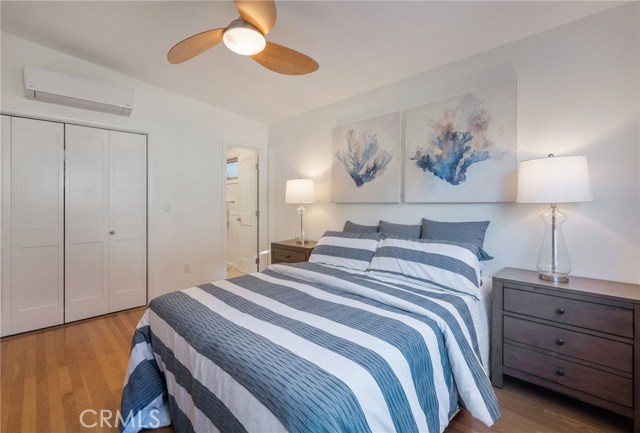 Back unit bedroom with air conditioning wall unit and door to en suite bathroom.