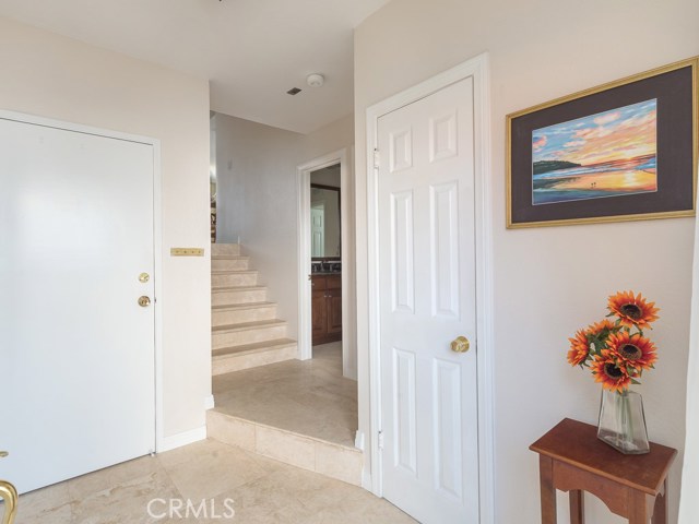 Nice entry with beautiful polished travertine floors welcomes you.  There is a bedroom (not visible in photo) and a remodeled 3/4 bath on this floor.  Direct access to extra-large two-car garage is through the door on the left. Stairs lead up to the main level.