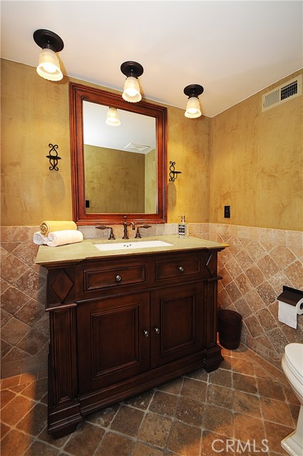 Powder room features Venetian plaster walls and stone floors and wainscotting.